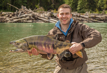 A happy sport fisherman holding up a big trophy Chum Salmon from the Kitimat River, Skeena Region, in British Columbia, Canada