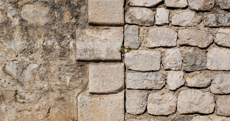 background of solid stone wall made of cement, limestone and light cobblestones with uneven surface