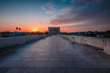 Sunrise in the Spanish city of Cordoba with dramatic morning clouds. Historic roman bridge in the...