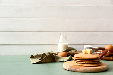 Board with tasty pancakes on table