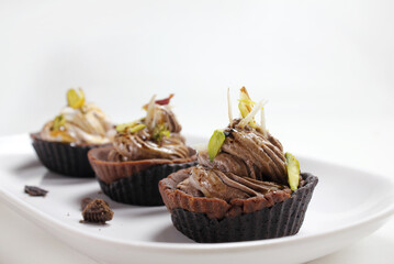 Homemade choco tart or mufins served with whipped cream,chocolate and dryfruits.