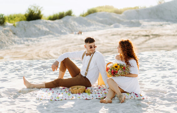 Lovely picnic on the sand near the lake in summer. Beautiful young couple