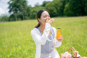 Fototapeta premium Asian woman going to drink fruit juice Which you prepared to picnic