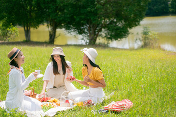  Asian woman friends. They are having a picnic, eating in the morning. They are talking.