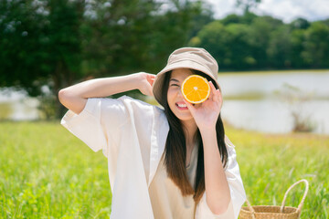 Asian woman she is showing orange She came to picnic with her friends.