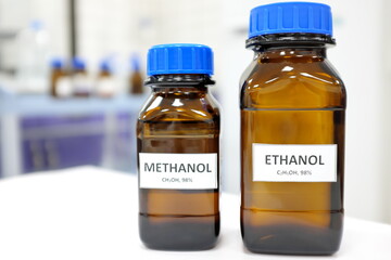 Selective focus of ethanol and methanol brown amber glass bottle inside a laboratory. Blurred...