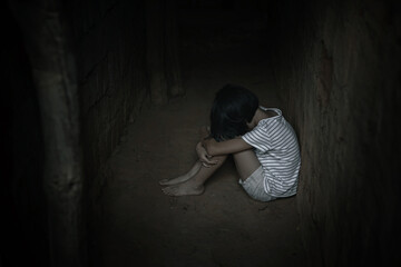 Kidnapped little girl sitting in old dark room. Human trafficking concept.