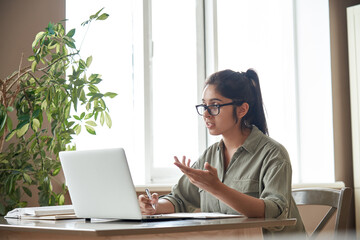Indian woman online tutor remote teacher wearing glasses speaking to webcam chat explaining online...