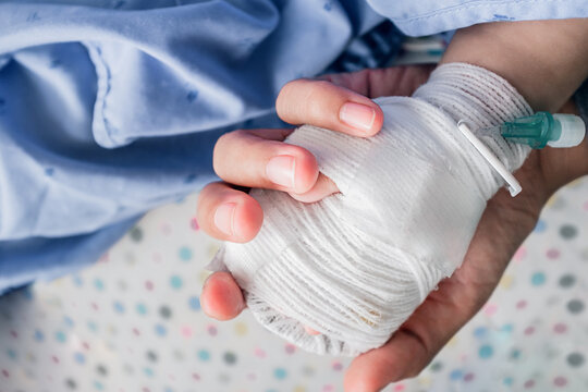Close-up pictures of the hands of an Asian baby tied in a white cloth to connect the saline cord.
