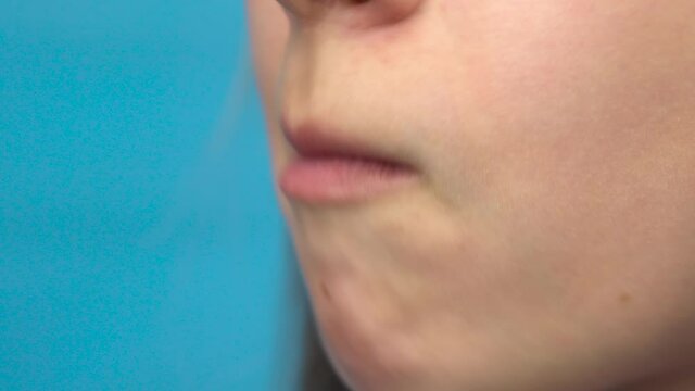 Teenage girl with braces on her teeth eats celery on a blue background. A girl with colored braces bites off a stalk of celery closeup.