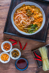 A bowl of snail noodles on a wooden table