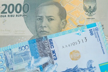 A macro image of a grey two thousand Indonesian rupiah bank note paired up with a blue, plastic five hunded tenge bank note from Kazakstan.  Shot close up in macro.