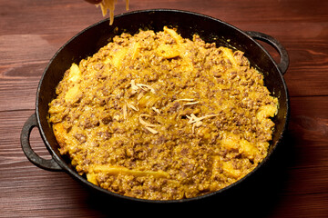 raw casseroles of potatoes and minced meat with cheese in a pan.