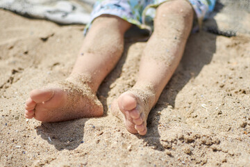 Feet of a child in the sand on the beach. The concept of carelessness and relaxation.