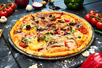 Pizza with mozzarella cheese, tomatoes, mushrooms, peppers, herbs on a dark wooden background.