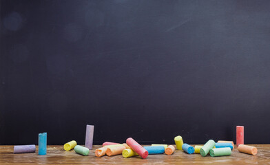 Group of colorful chalk on blackboard or chalkboard as background. School education, dark wall...