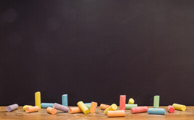 Group of colorful chalk on blackboard or chalkboard as background. School education, dark wall backdrop or learning concept.