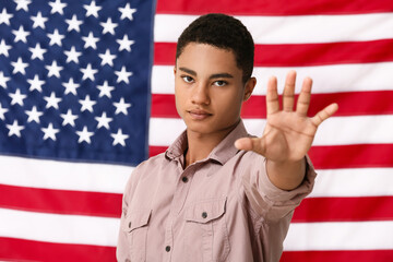 Sad African-American teenage boy near national flag of USA. Stop racism