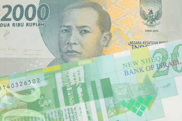A macro image of a grey two thousand Indonesian rupiah bank note paired up with a green and white fifty shekel bank note from Israel.  Shot close up in macro.