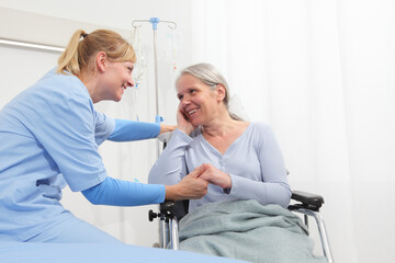 smiling nurse take comfort elderly woman isolated on wheelchair near bed in hospital room, concept of loneliness and old age diseases