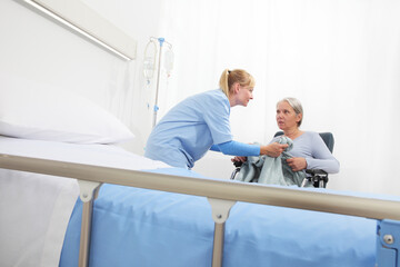 Obraz premium nurse take care elderly woman isolated on wheelchair near bed in hospital room, concept of loneliness and old age diseases