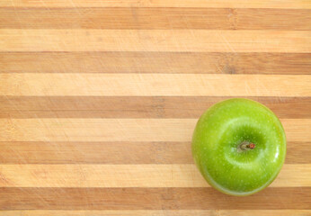 green apple sit on a worn butcher block cutting board