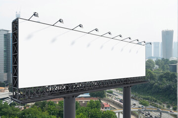 Obraz premium Blank white road billboard with KL cityscape background at day time. Street advertising poster, mock up, 3D rendering. Side view. The concept of marketing communication to promote or sell idea.