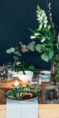 Set table with green plants, dark background. Healthy salad with beets on the plate
