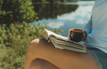 Woman reading a book near camping tent by the lake.