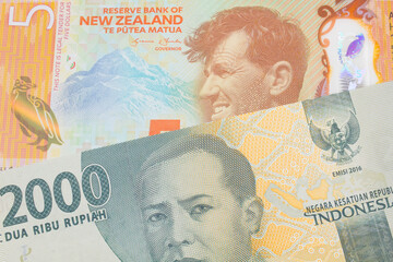 A macro image of a grey two thousand Indonesian rupiah bank note paired up with a orange, plastic five dollar bill from New Zealand.  Shot close up in macro.