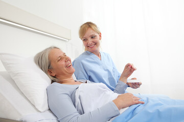 Obraz premium nurse gives the pill to the elderly woman patient lying in the hospital room bed, concept of loneliness and old age diseases