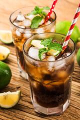 Fresh made Cuba Libre with brown rum, cola, mint and lemon on wooden background
