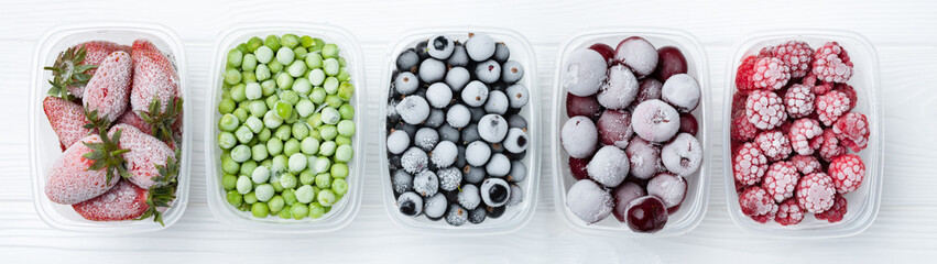Frozen berries and vegetables in plastic boxes on a light background. Web banner
