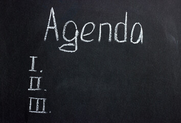 The inscription on a dark board Agenda with serial numbers. Plan of discussion of the arisen questions