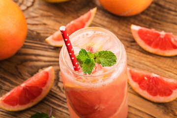 A glass of ripe grapefruit with juice on wooden table close-up