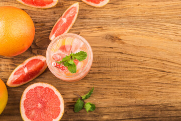 A glass of ripe grapefruit with juice on wooden table close-up