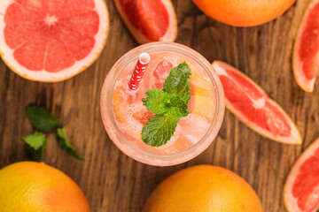 A glass of ripe grapefruit with juice on wooden table close-up
