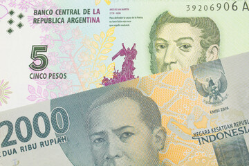 A macro image of a grey two thousand Indonesian rupiah bank note paired up with a colorful five peso note from Argentina.  Shot close up in macro.