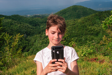 Beautiful nine year old girl takes a selfie in nature in the mountains