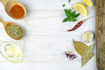 kitchen flat lay with spicy, lemon, garlic, oil, basil and cutting board. cooking light background