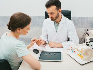 A young audiologist selects a hearing aid for a caucasian woman. Patient needs good hearing aids so...