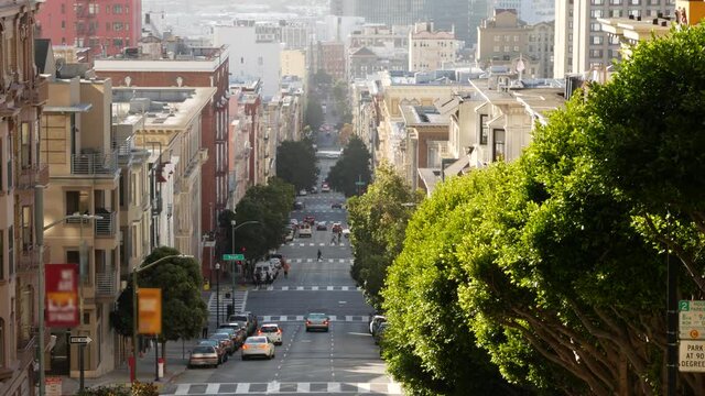 Iconic hilly street and crossroads in San Francisco, Northern California, USA. Steep downhill road and pedestrian walkway. Downtown real estate, victorian townhouses abd other residential buildings.
