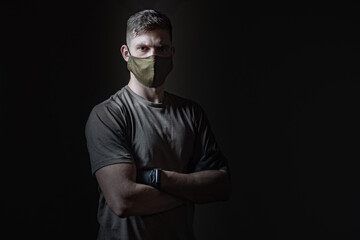 Fabric medical bandages. Young guy in gloves and a mask. Human on a dark background. Concept - volunteer helping infected people. Concept - young man infected with a pandemic. Dark background