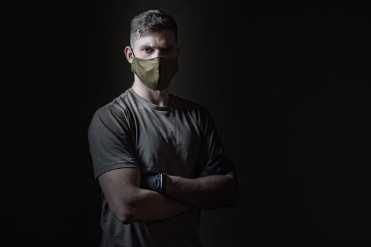 Fabric medical bandages. Young guy in gloves and a mask. Human on a dark background. Concept - volunteer helping infected people. Concept - young man infected with a pandemic. Dark background
