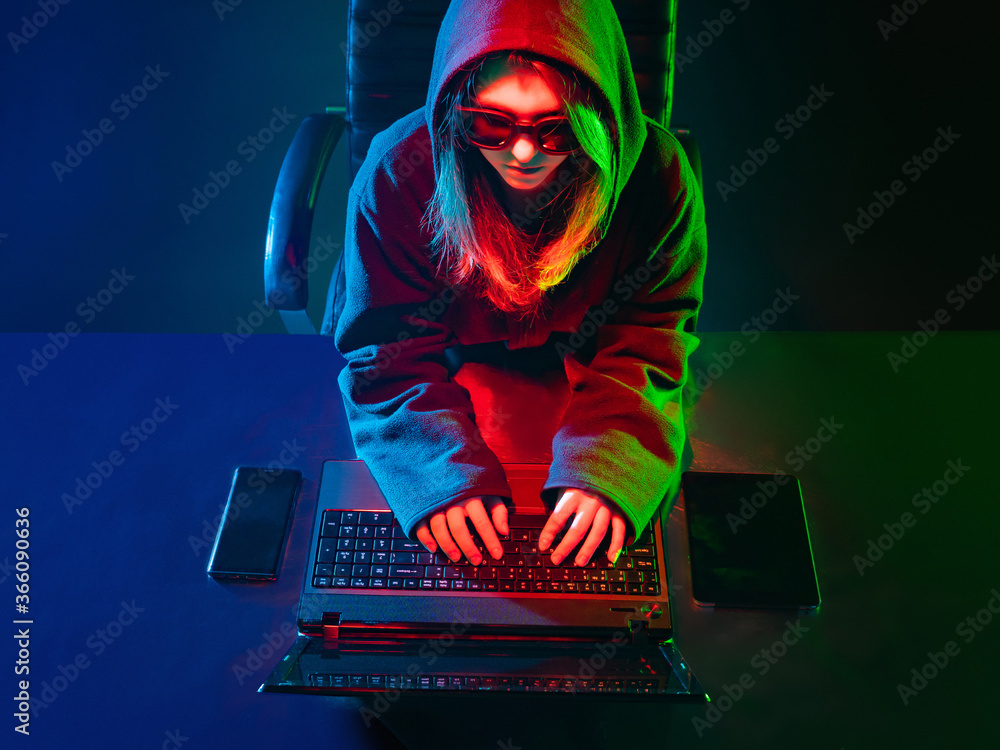 Poster girl is a hacker. girl next to a laptop top view. hacker attack. woman gamer in a neon light. concep