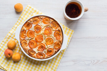 homemade apricot pie in a white form on a light wooden background, delicious pastries, summer dessert