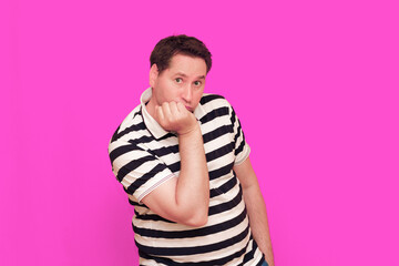 Caucasian man wearing casual striped t-shirt standing over isolated hot pink background shows...