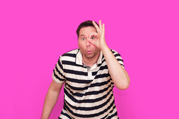 Caucasian man wearing casual striped t-shirt standing over isolated hot pink background shows...