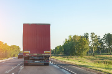Rear view of a truck with a red body on a road, delivering and transporting cargo by a transport...