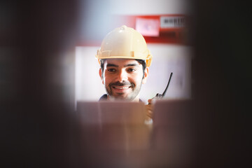 Male dispatcher, warehouse worker checking packages while using walkie-talkie in distribution...